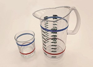 Glas och tillbringare med röd och blå rand, som visar hur mycket saft respektive vatten som ska fyllas i.